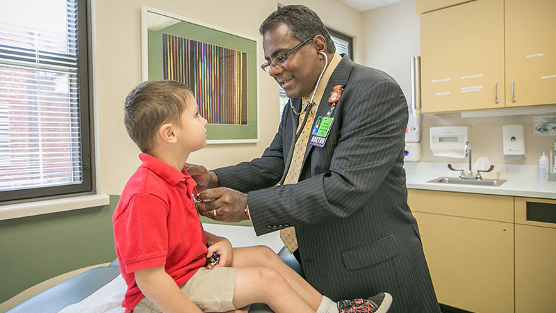A doctor checking a little boy's heartbeat